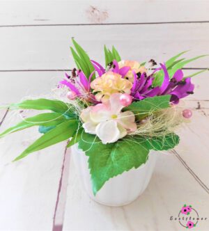 Topfgesteck mit lila-rosa Blüten im weißen Topf